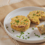 Schinken-Käse-Puffer auf einem weißen Teller, dekoriert mit Schnittlauch.